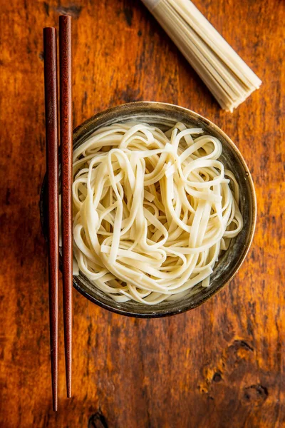 Cooked udon noodles. Traditional Japanese noodles in plate on wooden table. Top view.