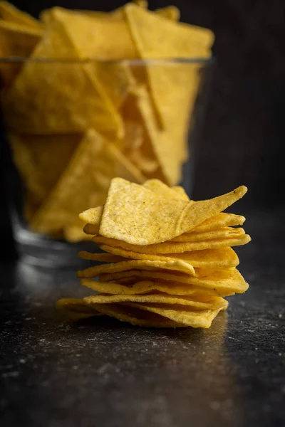 Salted tortilla chips on black table.