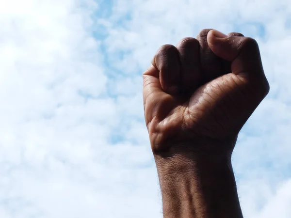 アフリカ系アメリカ人の手を握り締め空を背景に力と黒の誇りを象徴する拳に — ストック写真