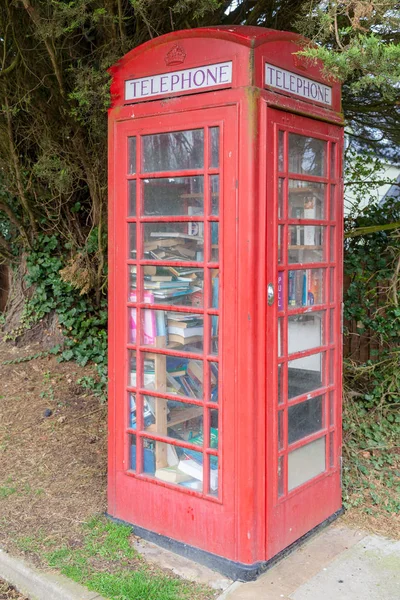 Red public telephone box in the UK. Phone booth full of books acting as a local mini library. Red phone boxes are very iconic in England and have been around since about 1924. Although these landmarks are still around, not all of them are working tel