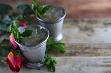Görüntü Kentucky Derby Mayıs ayında kırmızı gül ve kopya alanı rustik bir ortamda iki gümüş sakinleşmek su bardağı ezilmiş buz ve taze nane ile gösterilen için