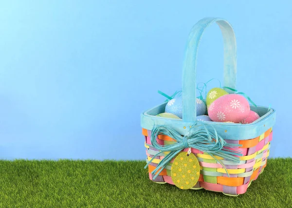 Cute Easter image with green grass and blue sky with colorful easter basket full of sparkly eggs. Copy space — Stock Photo, Image