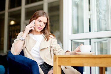Kafede telefon ve kahveli genç bir kadın.