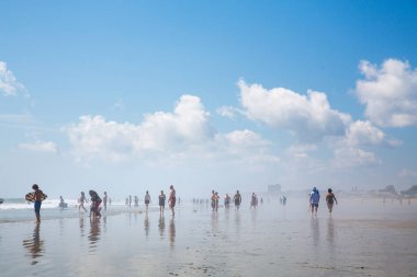 Old Orchard Beach, Maine, USA - September 1, 2014: People enjoying sea and sunshine. Heat haze of evaporating water, reflected blue sky. clipart