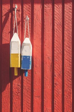 Fishing buoys, used to mark where the lobster pots are dropped, hanging on a red wooden wall in Prince Edward Island, Canada. Spcae for your text. clipart