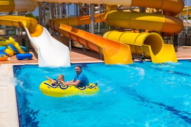 Baba ve küçük oğlu eğleniyor kaydırağı üzerinde güneş tatil sırasında