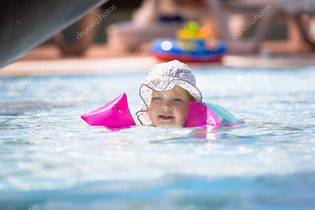 Little girl swimming in armbands on summer vacation