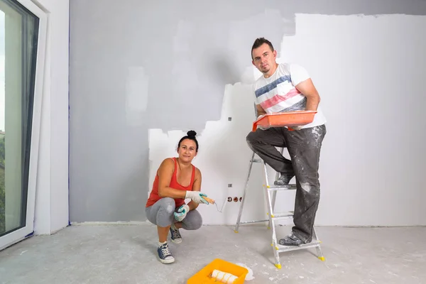 Couple painting a room with paint rollers