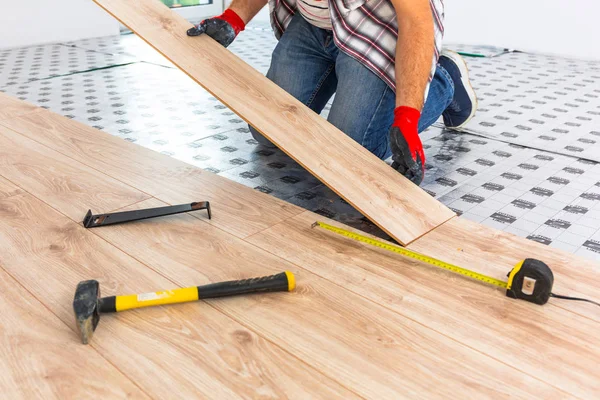 Handyman installing new laminated wooden floor — Stock Image Handyman Installing New Laminated Wooden Floor Royalty Free Stock Images