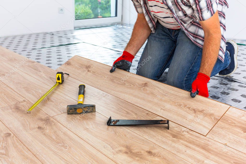 Handyman installing new laminated wooden floor