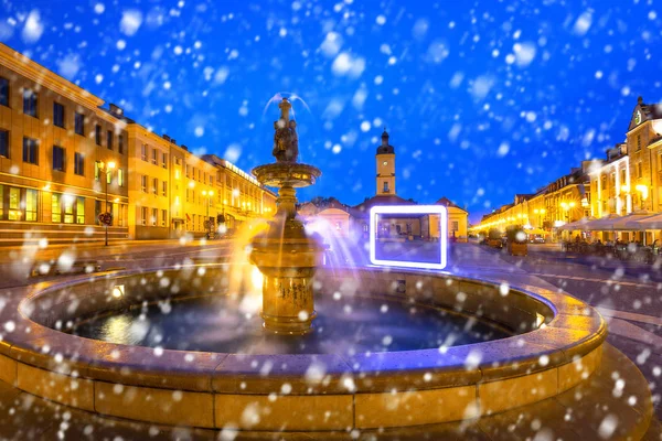 Fountain on the main square of Bialystok at night with falling snow, Poland.