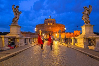 Rome, Italy - January 9, 2019: Men in Roman soldier costumes the Saint Angel bridge in Rome at dusk, Italy