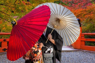 Geleneksel Japon şemsiye Kyoto sonbahar Park'ta poz ile çift