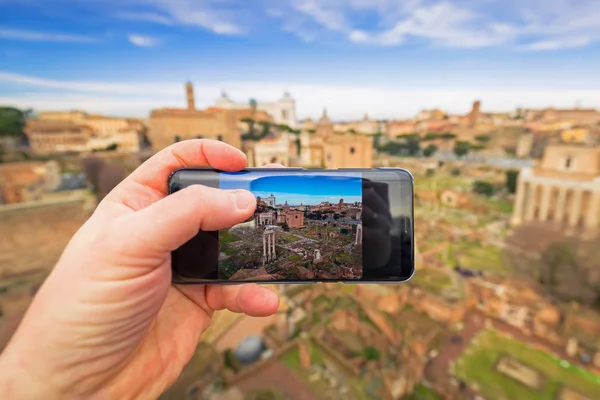 Hand with mobile camera making photo of the Roman Forum in Rome, Italy