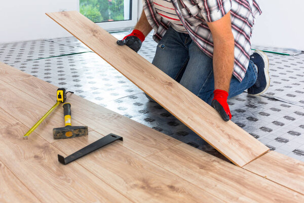 Handyman installing new laminated wooden floor