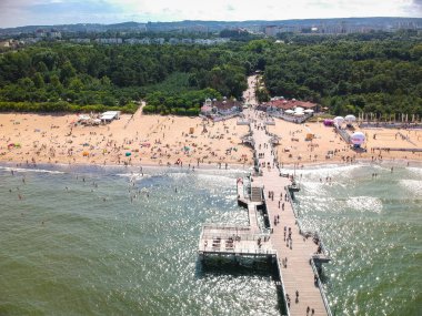 Gdansk, Polonya - 3 Ağustos 2019: Gdansk, Polonya'da Baltık Denizi'nde ahşap iskele ile sahilde dinlenen insanlar.