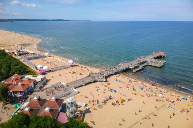 Gdansk, Polonya - 3 Ağustos 2019: Gdansk, Polonya'da Baltık Denizi'nde ahşap iskele ile sahilde dinlenen insanlar.