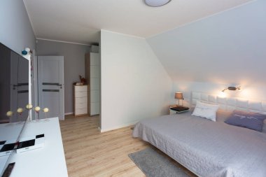 Büyük yatak odası gri ve beyaz renklerde.