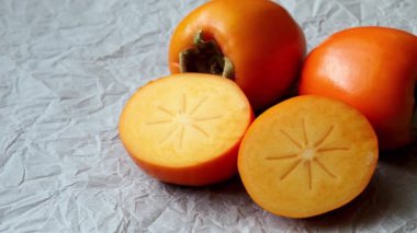 Bütün ve taze olgun hurma yarısı. Japonca Trabzon hurması (Diospyros kaki)