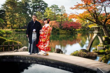 Geleneksel kimonolu Japon düğün çifti Kenrokuen Park, Kanazawa, Japonya 'da bir köprüde duruyor.