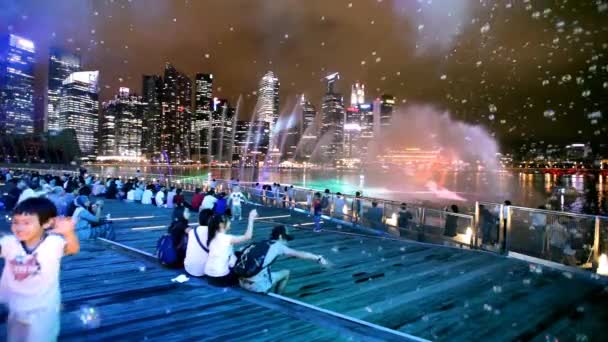 İnsanlar Singapur 'daki Marina Bay Sands' de dans eden fıskiyelerin ücretsiz ışık ve su gösterisinin keyfini çıkarıyorlar. — Stok video