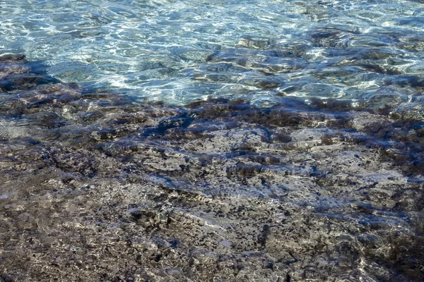 Eau claire de la Méditerranée avec pierre et fond sablonneux — Photo