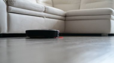 Robot elektrikli süpürge toz beyaz kanepe yakınındaki odasında toplar.