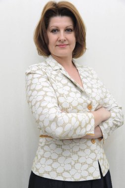 Gülümseyen hafif bir arka plan üzerinde bir ceketli orta yaşlı kadın