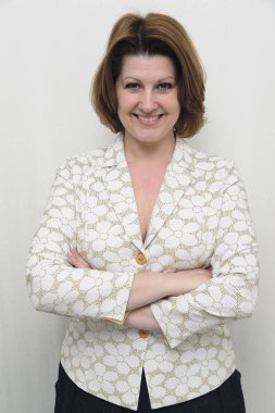 Gülümseyen hafif bir arka plan üzerinde bir ceketli orta yaşlı kadın