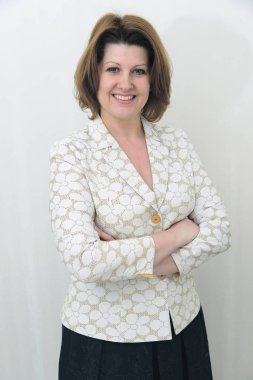 Gülümseyen hafif bir arka plan üzerinde bir ceketli orta yaşlı kadın