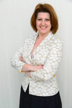 Gülümseyen hafif bir arka plan üzerinde bir ceketli orta yaşlı kadın