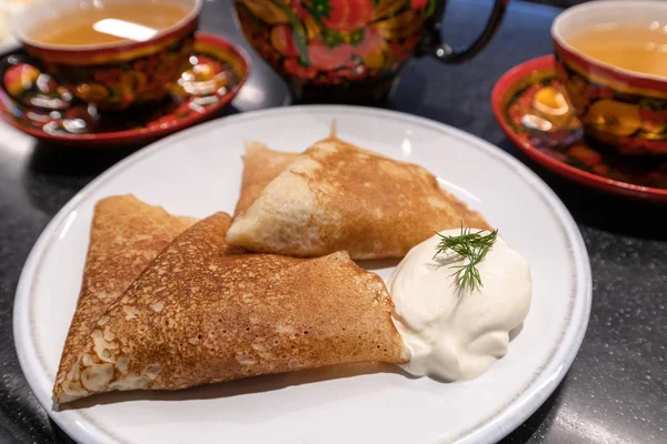 マースレニツァの休日のための伝統的な料理でお茶とサワー クリームのパンケーキ — ストック写真