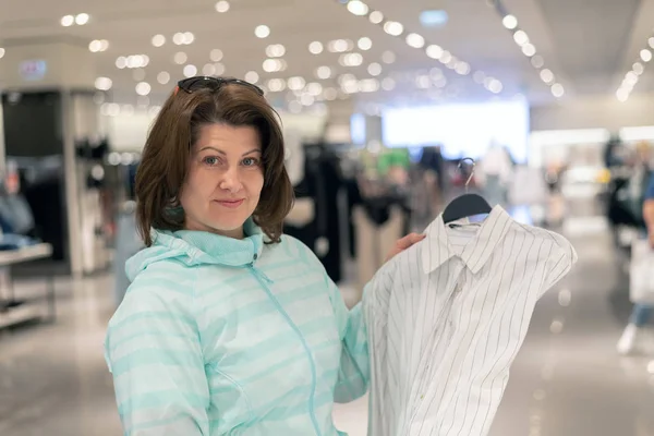 La Mujer elige blusa en la tienda — Foto de Stock