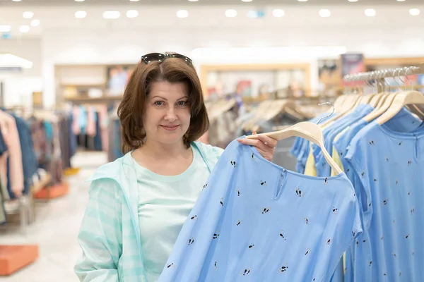 La Mujer elige la ropa en la tienda — Foto de Stock