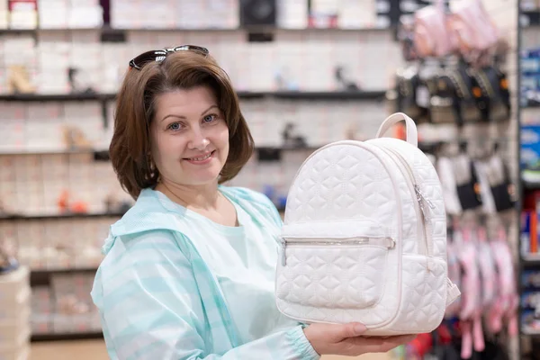 Женщина выбирает сумки рюкзак в магазине — стоковое фото