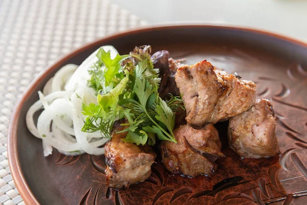 Partes de shashlik com ketchup e cebolas em uma chapa — Fotografia de Stock