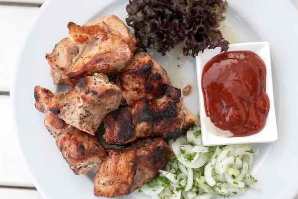 Bitar av Shashlik med ketchup och lök på en tallrik — Stockfoto