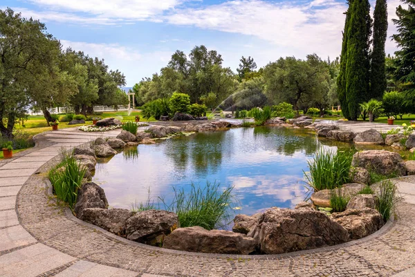 Fragmento de hermoso jardín con un estanque artificial en verano —  Fotos de Stock