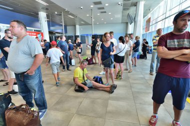 Tivat, Karadağ - 10 Ekim. 2019. Uluslararası Tivat havaalanının kalabalık bir kalkış salonunda insanlar yerde oturuyor.