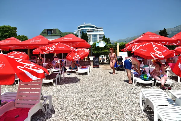 Budva, Czarnogóra - 13 czerwca 2019 r. Plaża miejska w kurorcie z czerwonymi parasolami z marką Coca Cola — Zdjęcie stockowe