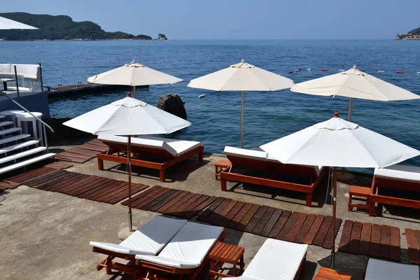 beach in resort area with white umbrellas in Budva, Montenegro