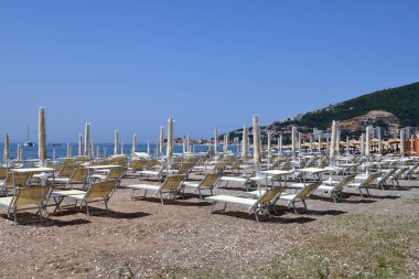 Budva, Karadağ - 13 Haziran 2019. Kapalı şemsiyeli tatil köyü sahili.