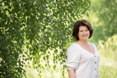 Yazın huş ağacının yanındaki Rus kadın.