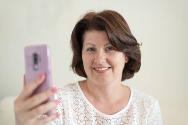 Cep telefonuna bakan bir kadının portresi.