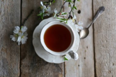 Tahta bir masada bir fincan çay ve badem çiçeği. 