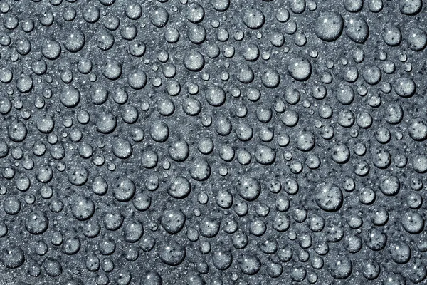 Üzerinde mavi bir arka plan şeffaf saf su damlacıkları. Damla su yakın çekim.