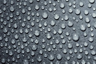 Üzerinde mavi bir arka plan şeffaf saf su damlacıkları. Damla su yakın çekim.