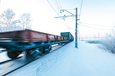 Yük treni karla kaplı demiryolu hareket ediyor.