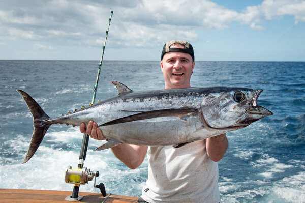 Happy angler holding big tuna fish 