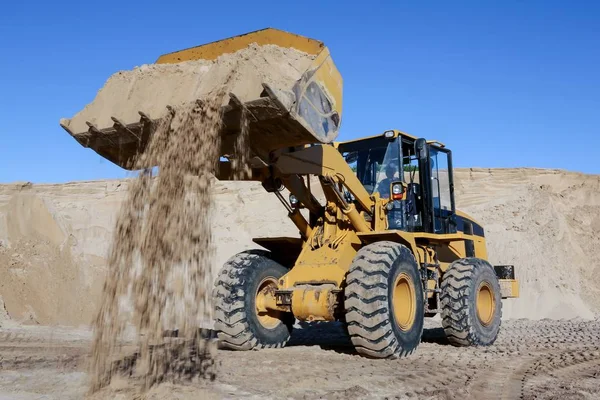 Cavar e carregar areia com uma máquina em uma pedreira Imagem De Stock